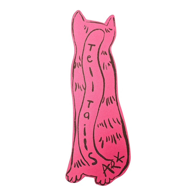 The back of a pink cat shaped bookmark with the text 'tell tails' written down the centre in black writing.