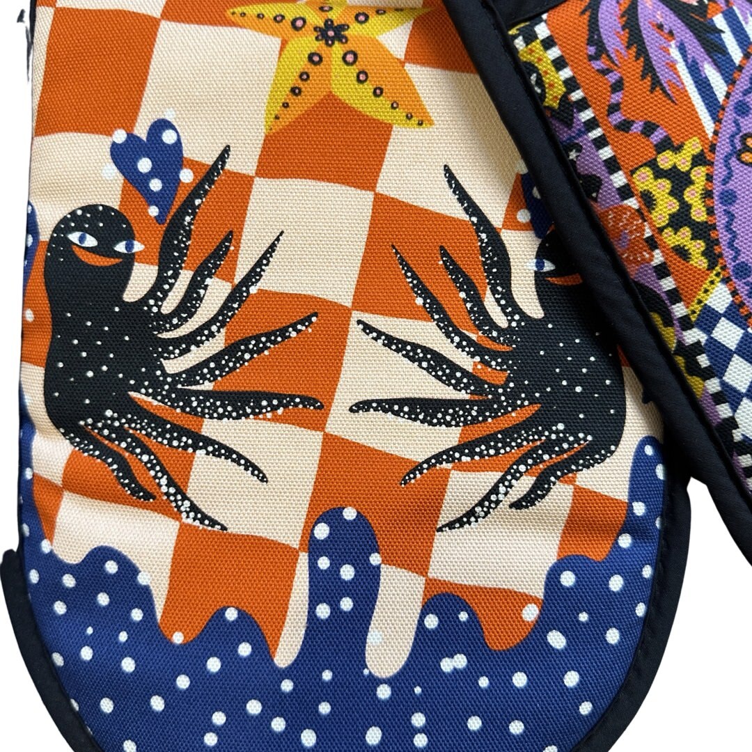 The inside of catch of the day oven gloves with happy black octopus against a red and white check background.
