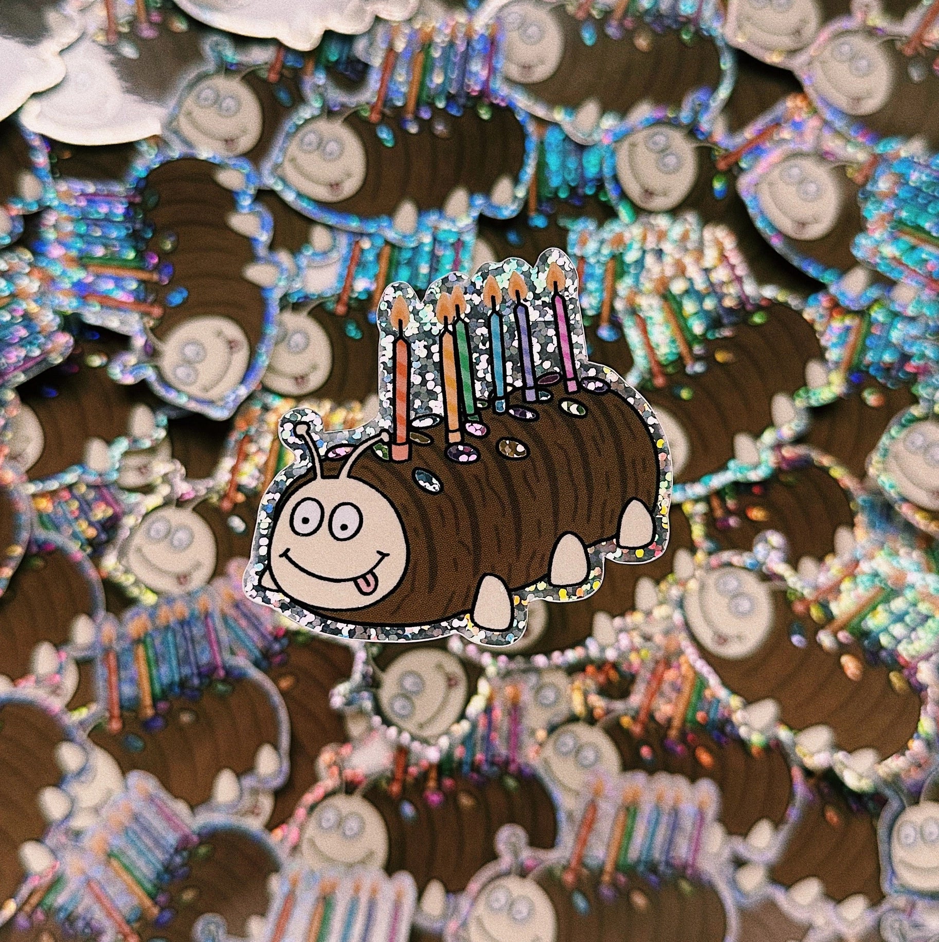 A waterproof holographic glitter vinyl sticker of a chocolate caterpillar cake.