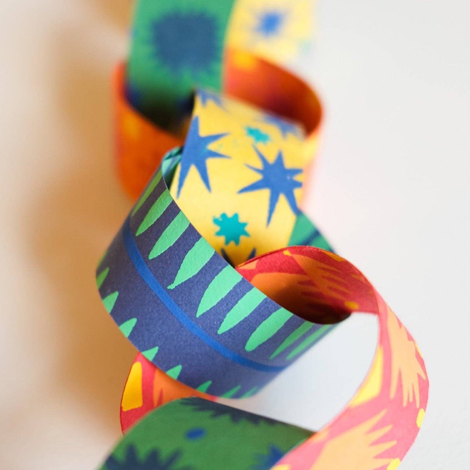 Colorful paper chain with abstract patterns on a blurred background.