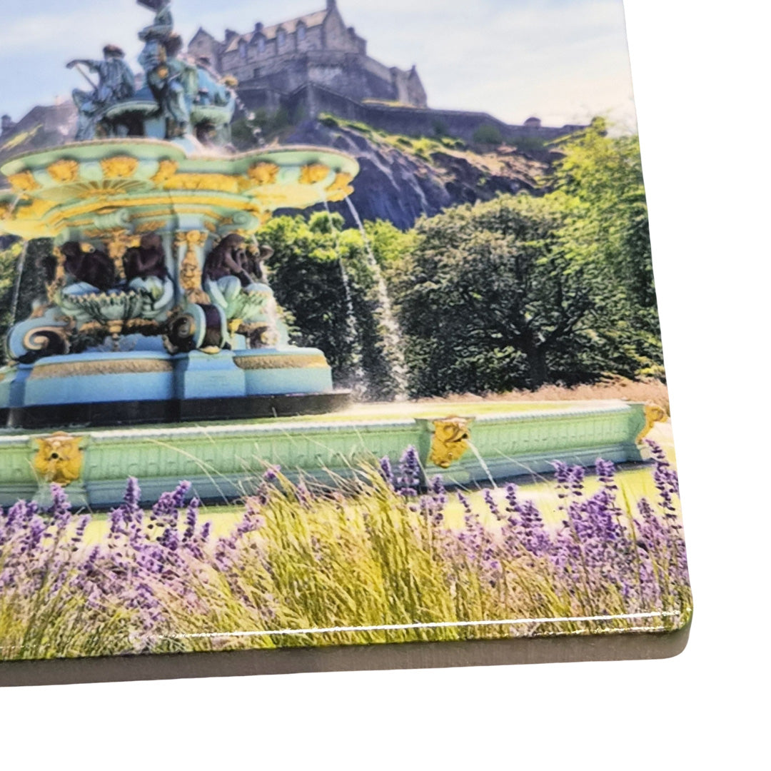 Fountain with statues and lavender in a garden setting, featuring a castle in the background.