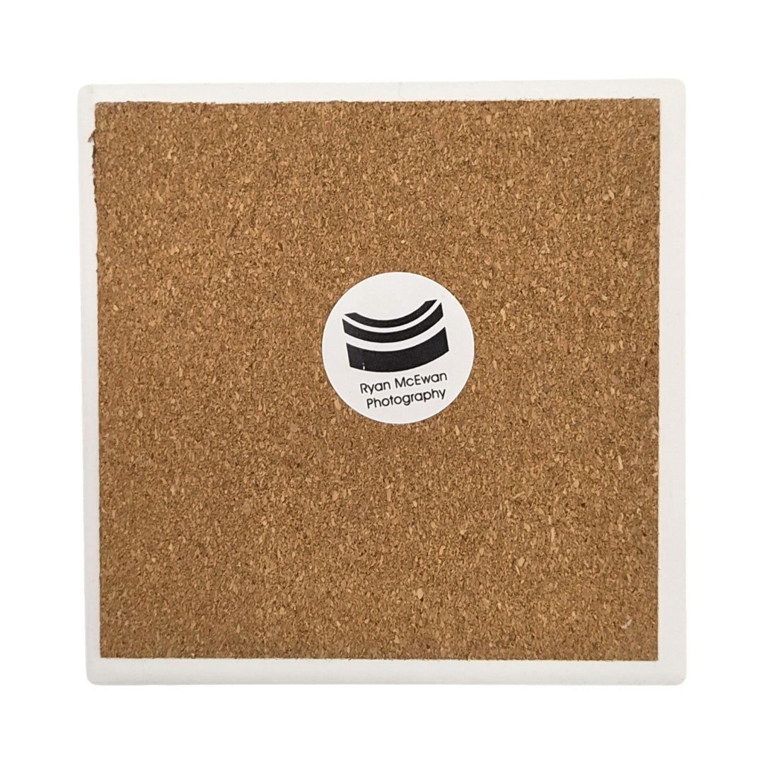 The back of a ceramic coaster showing a cork backing and a label that says Ryan McEwan Photography.