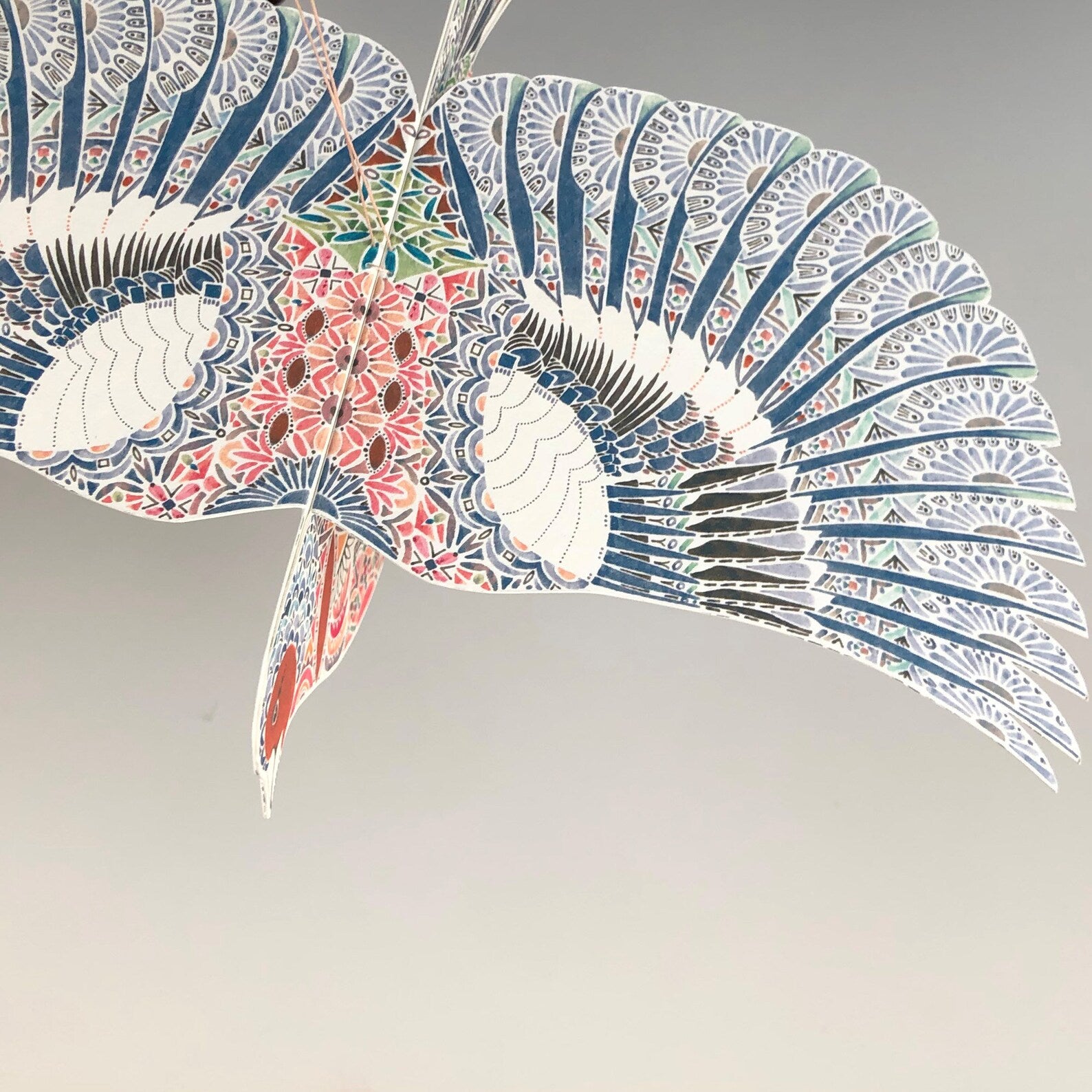 Decorative paper bird with intricate patterns on a plain background.