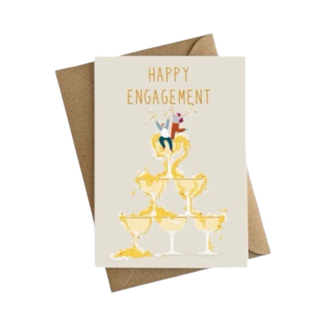 Engagement card featuring an illustration of a couple celebrating on the top of a champagne glass with the champagne cascading over into more glasses and the text 'Happy Engagement'.