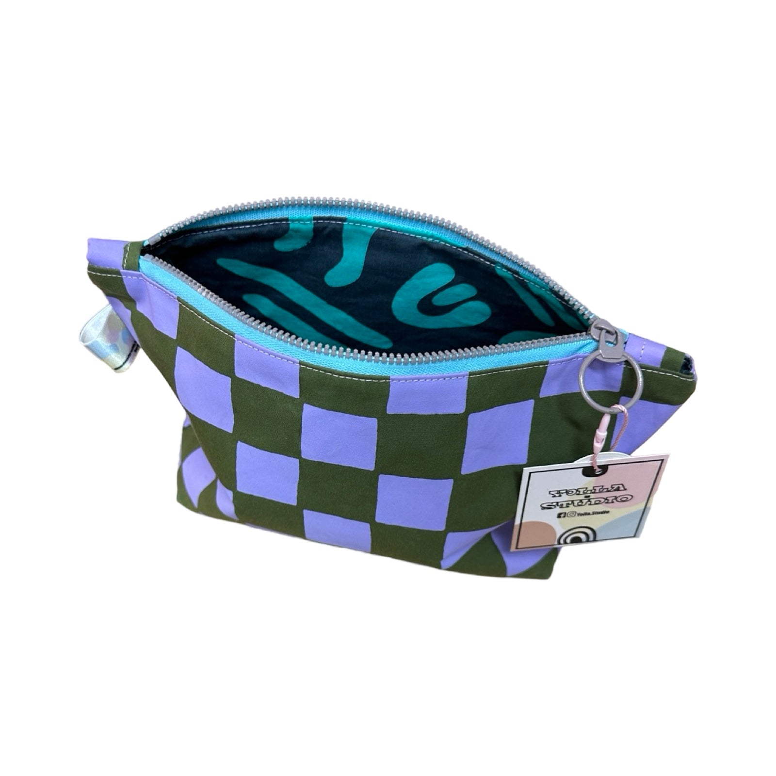 A grey and purple checked cosmetic bag open showing turquoise and blue abstract lining.