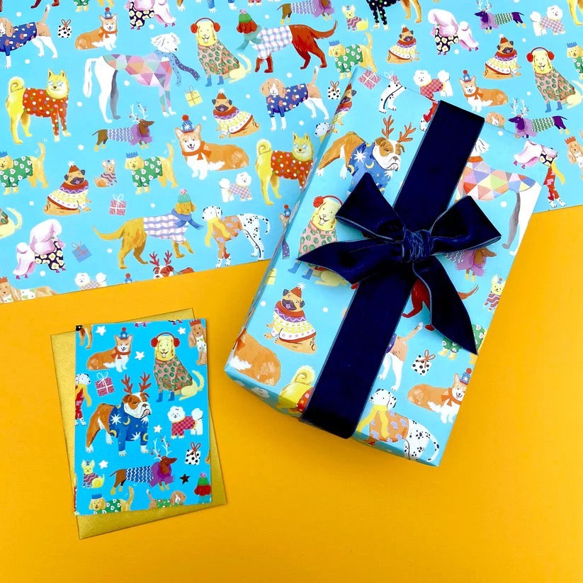 Gift box with blue ribbon on a blue wrapping paper with Christmas dog pattern, on a yellow background.