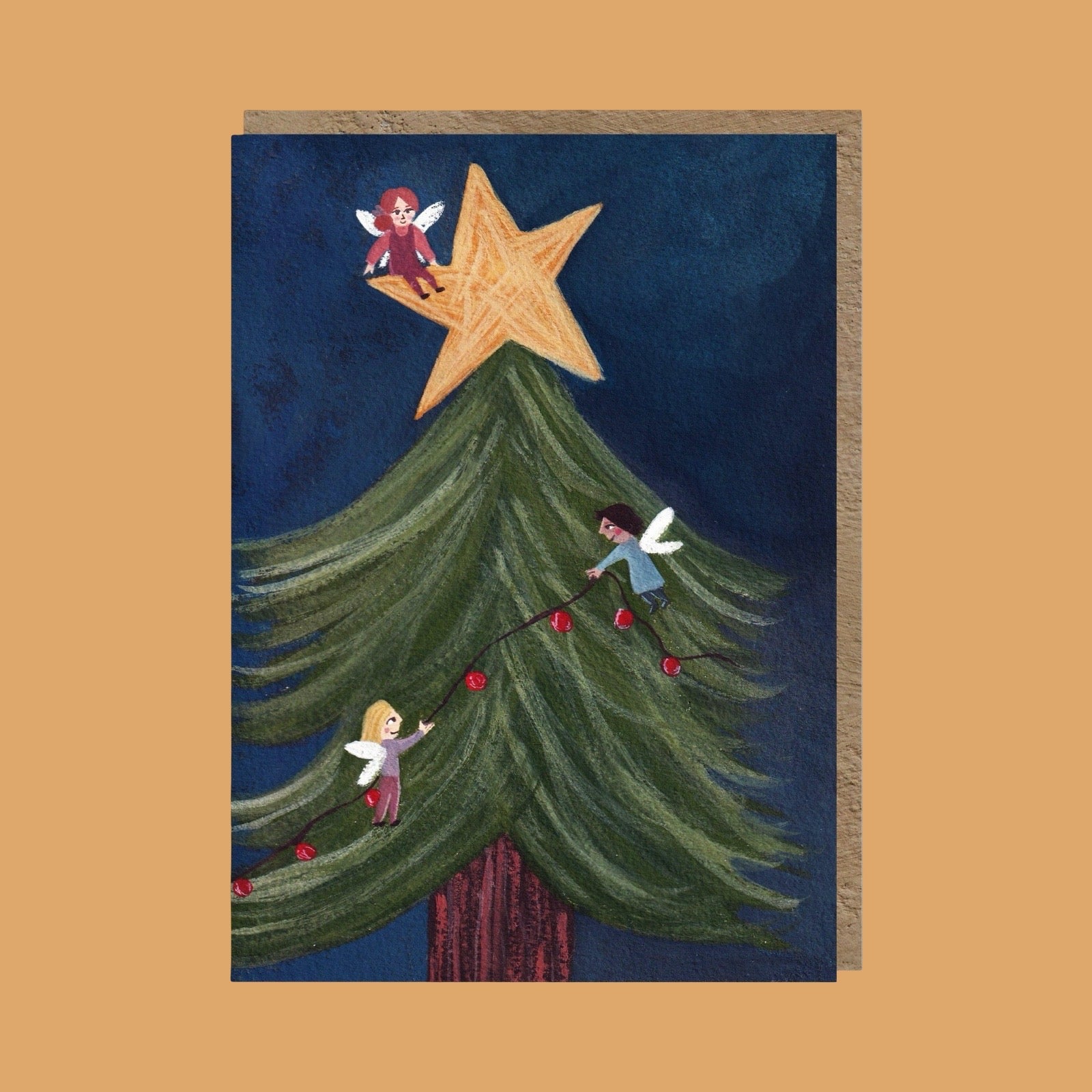 A card featuring a whimsical Christmas tree illustration with three fairy-like children climbing the tree and a large gold star on top, shown against a warm tan background.