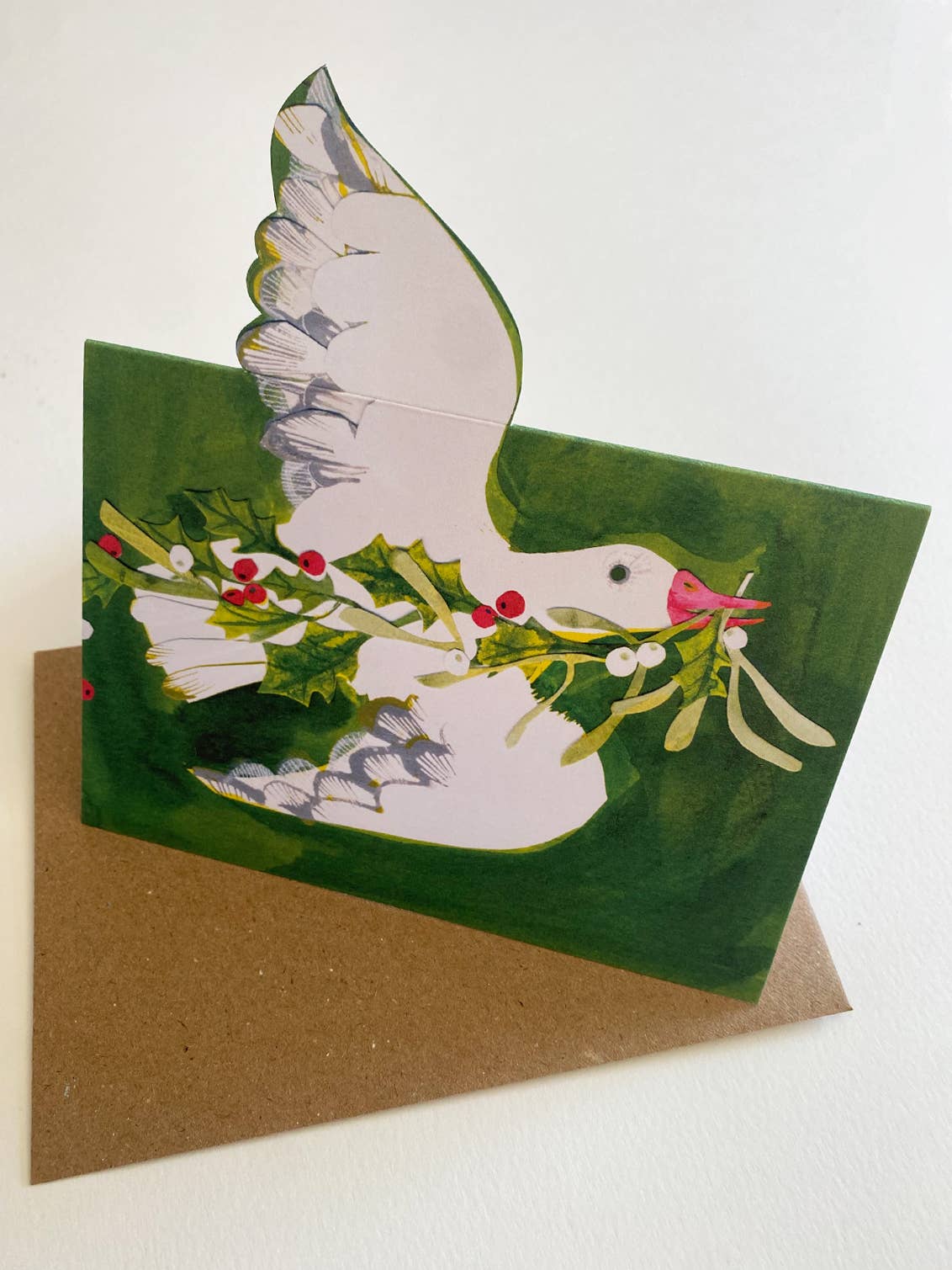 Greeting card with a goose holding mistletoe on a green background