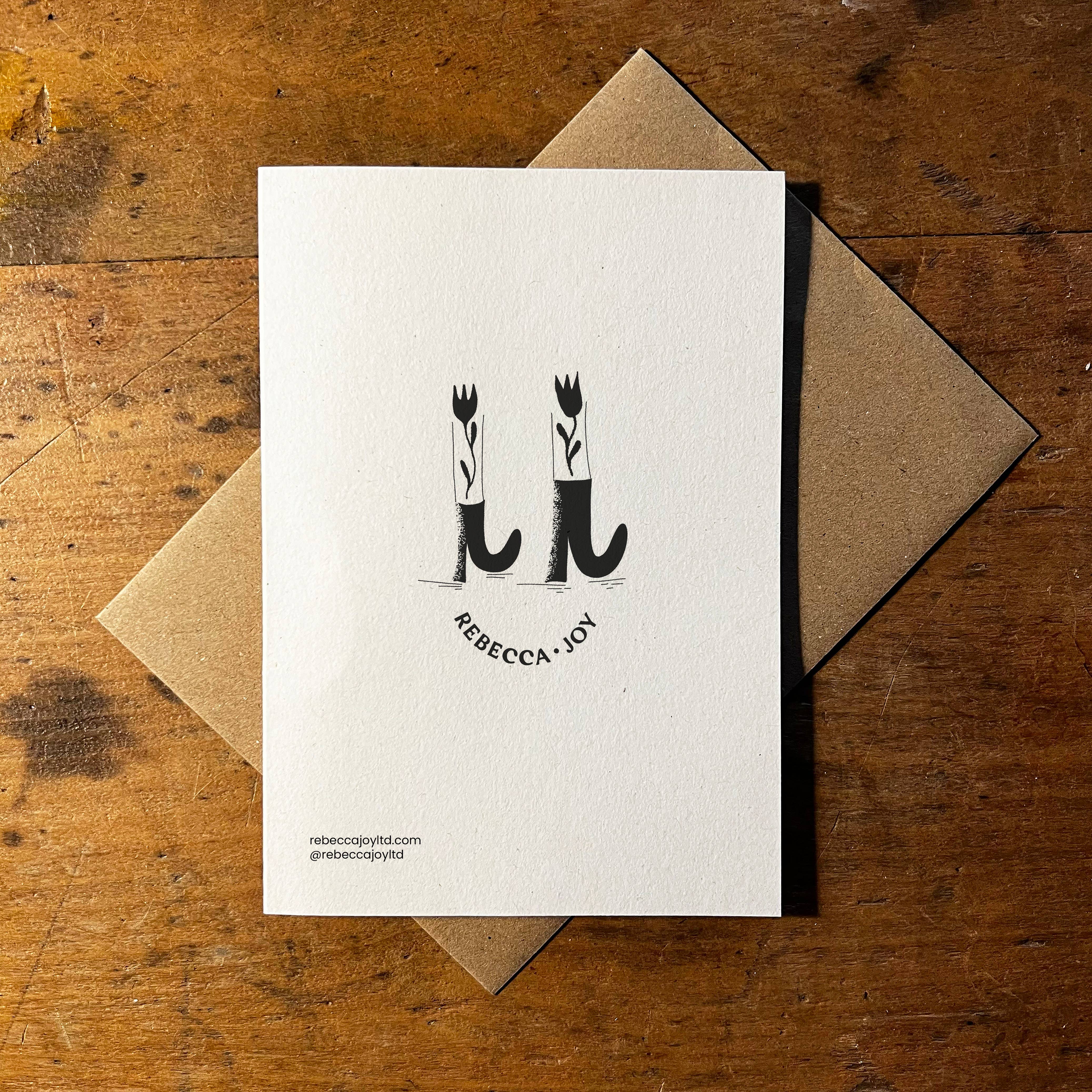 Back of card with an brown envelope on a wooden table.