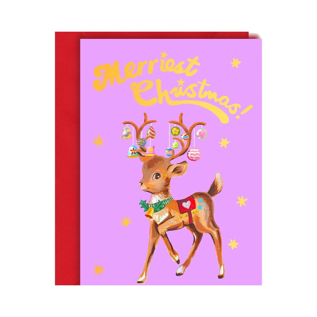 A Christmas card featuring a reindeer with a bell around its neck and Christmas baubles hanging from its antlers, with the text 'Merriest Christmas!' in gold. The card is blank inside and has a gold envelope.