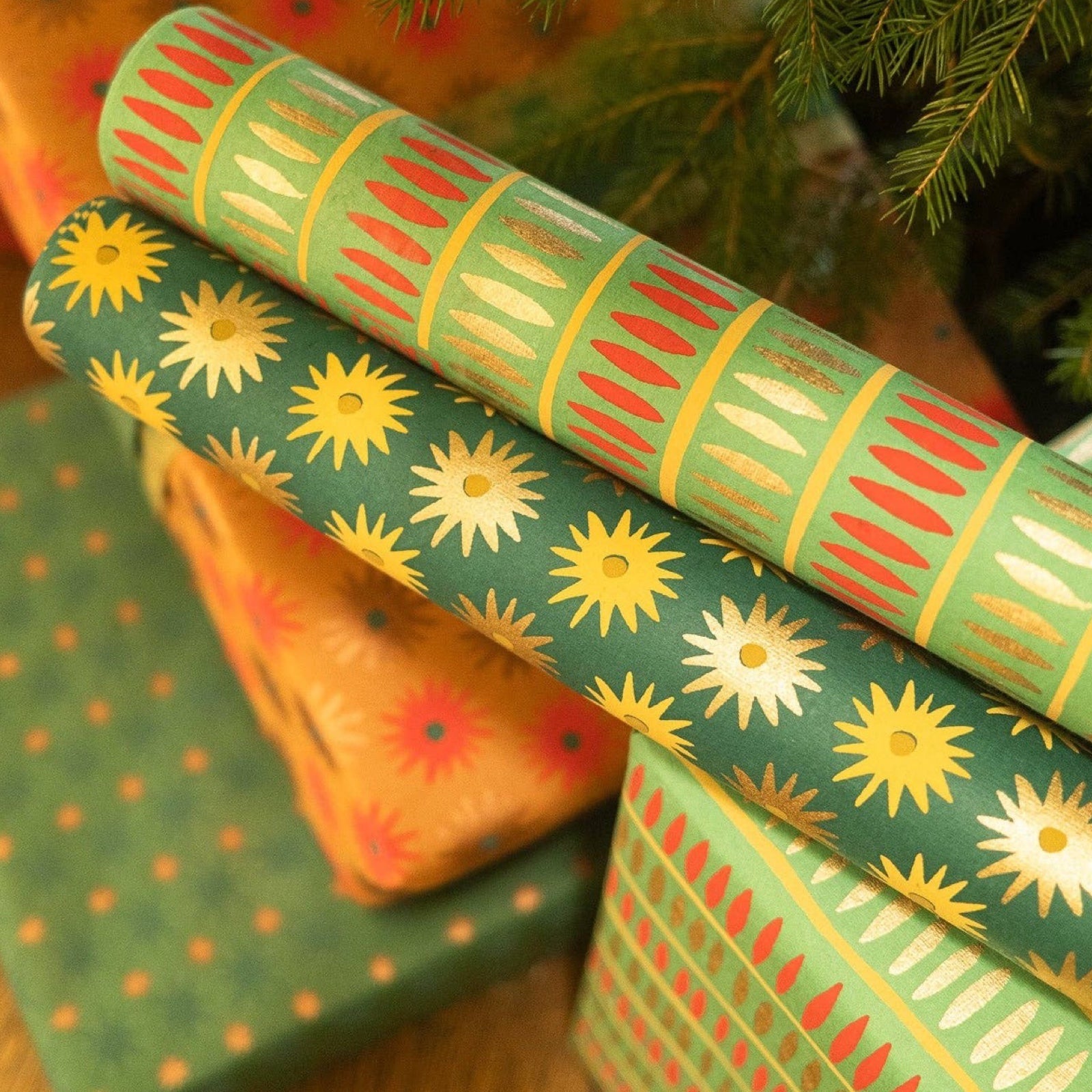 Gorgeous screen-printed Christmas wrapping paper with gold and red dashes against a green background.