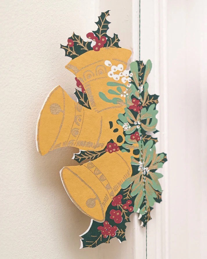 Decorative Christmas bell garland with holly leaves and berries on a white background.