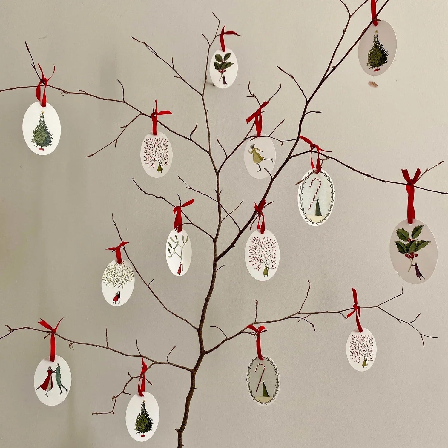Decorative Christmas tags on branches with a neutral background.