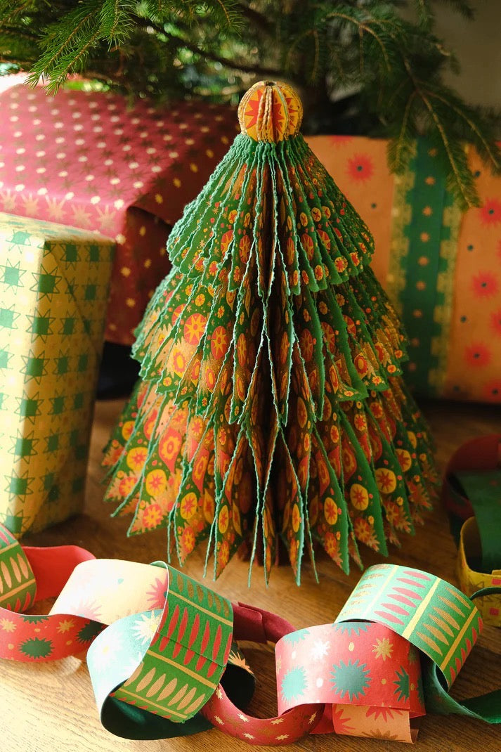 Decorative paper Christmas tree with colourful paper chains and wrapped presents in the background.