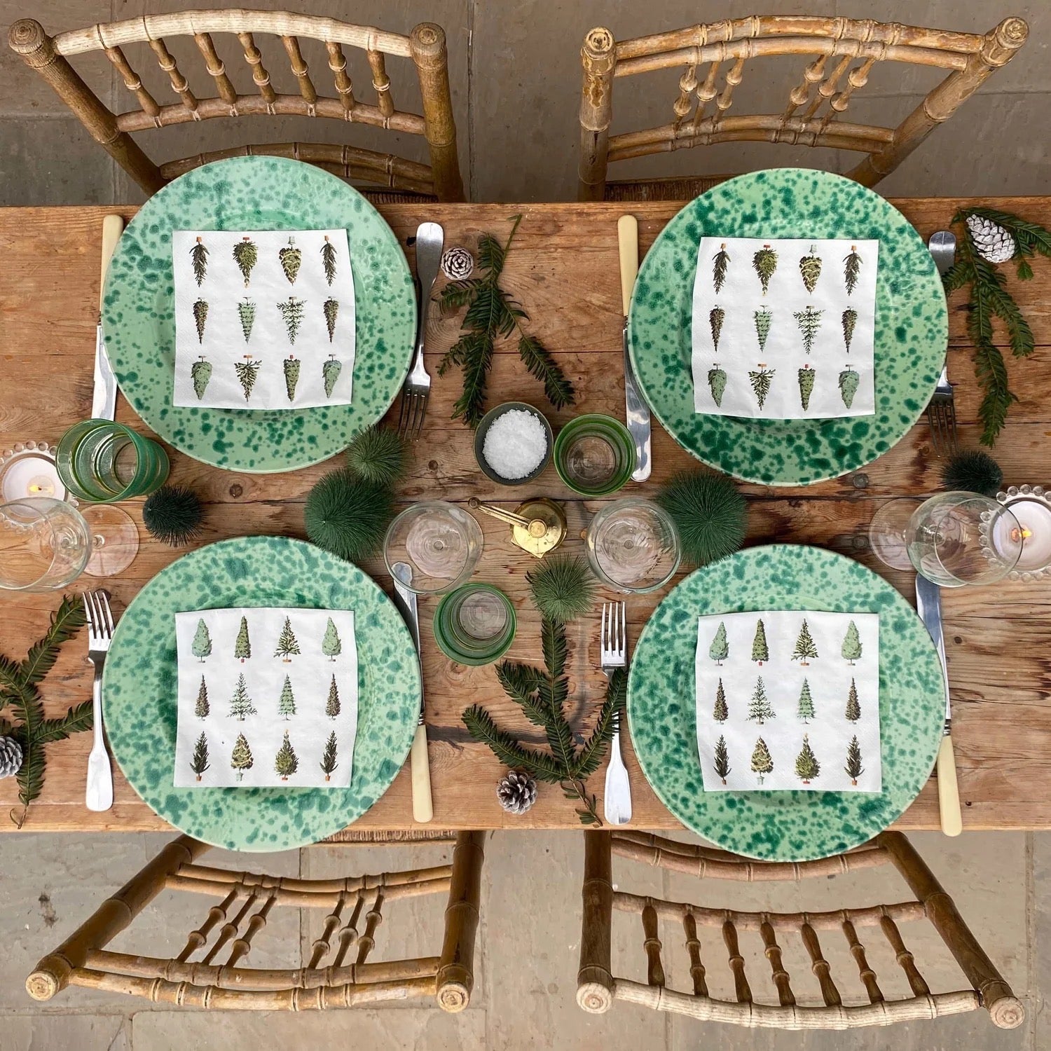 Set dining table with green plates, napkins, and decorative elements on a wooden surface.