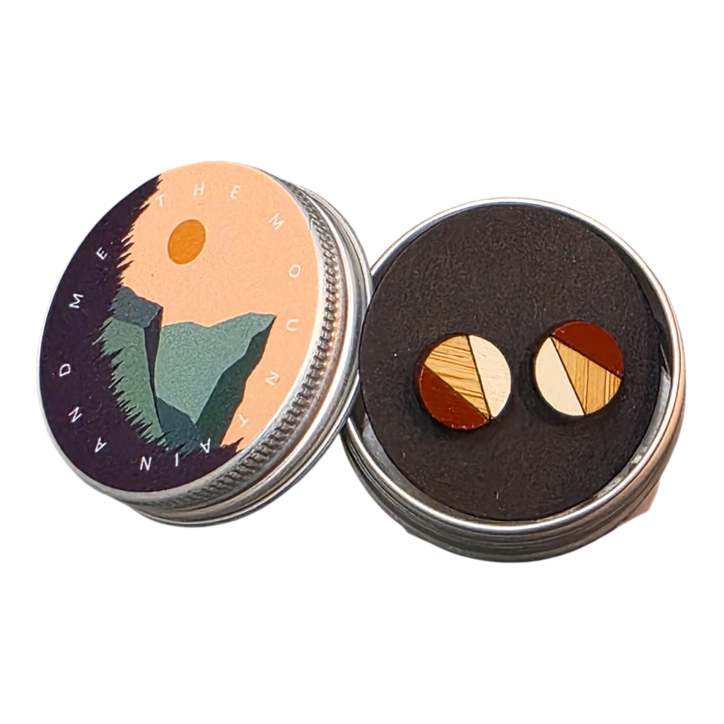 A pair of red and white painted circular wooden stud earrings in a small metal tin.