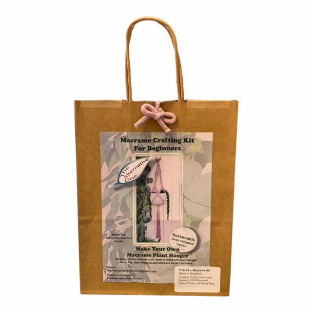 A Classic Macrame Plant Hanger Kit packaged in a brown paper bag displaying the contents, including pre-cut macrame cords and a wooden hanging ring.