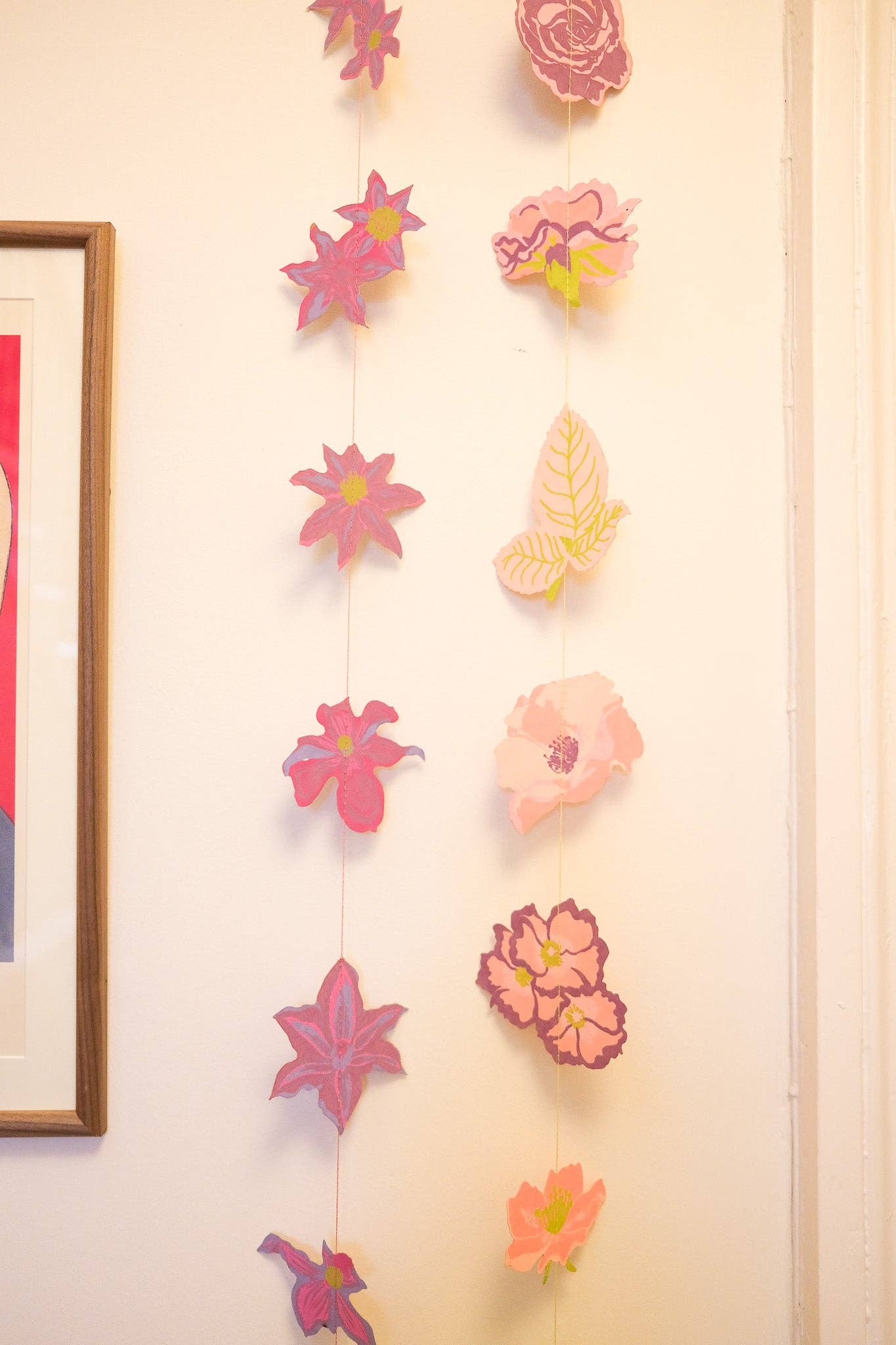 Decorative paper flowers hanging on a wall with a framed picture.