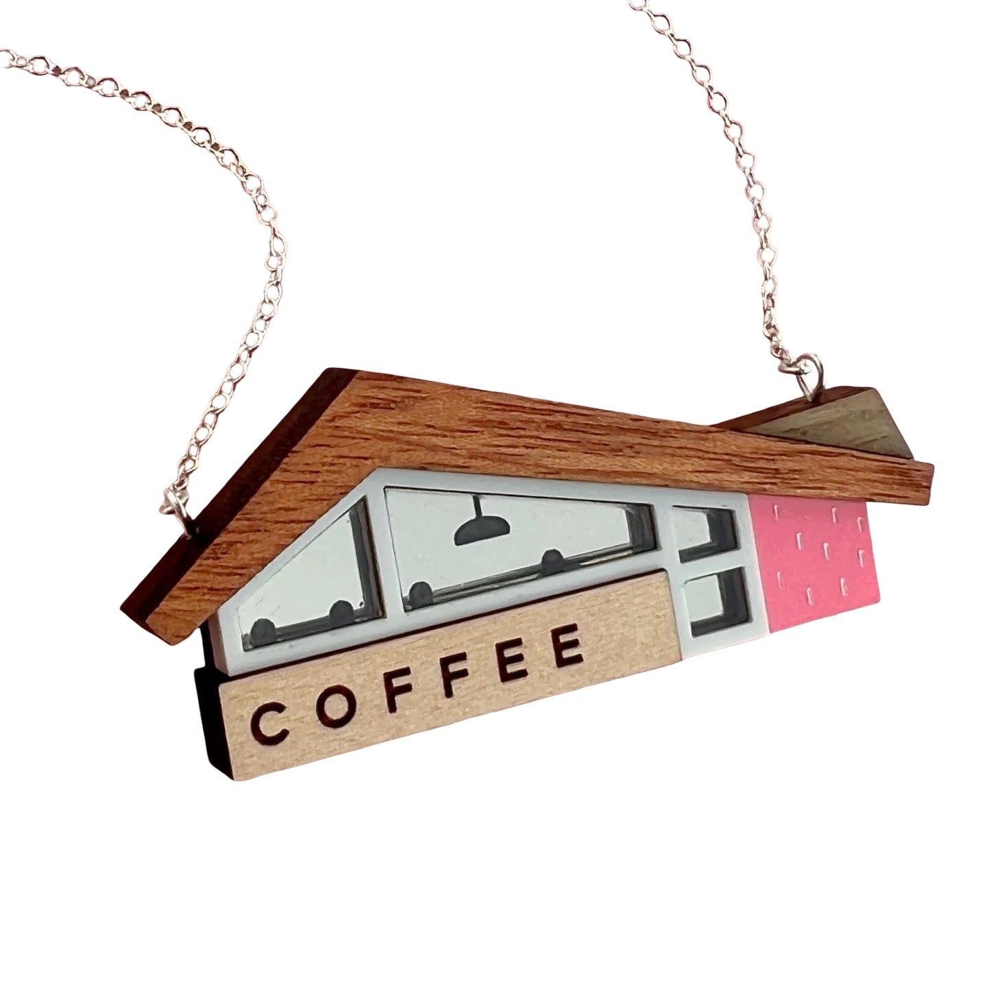 This necklace features a retro-inspired American coffee shop as a pendant, with a wooden roof and a coral pink wall.
