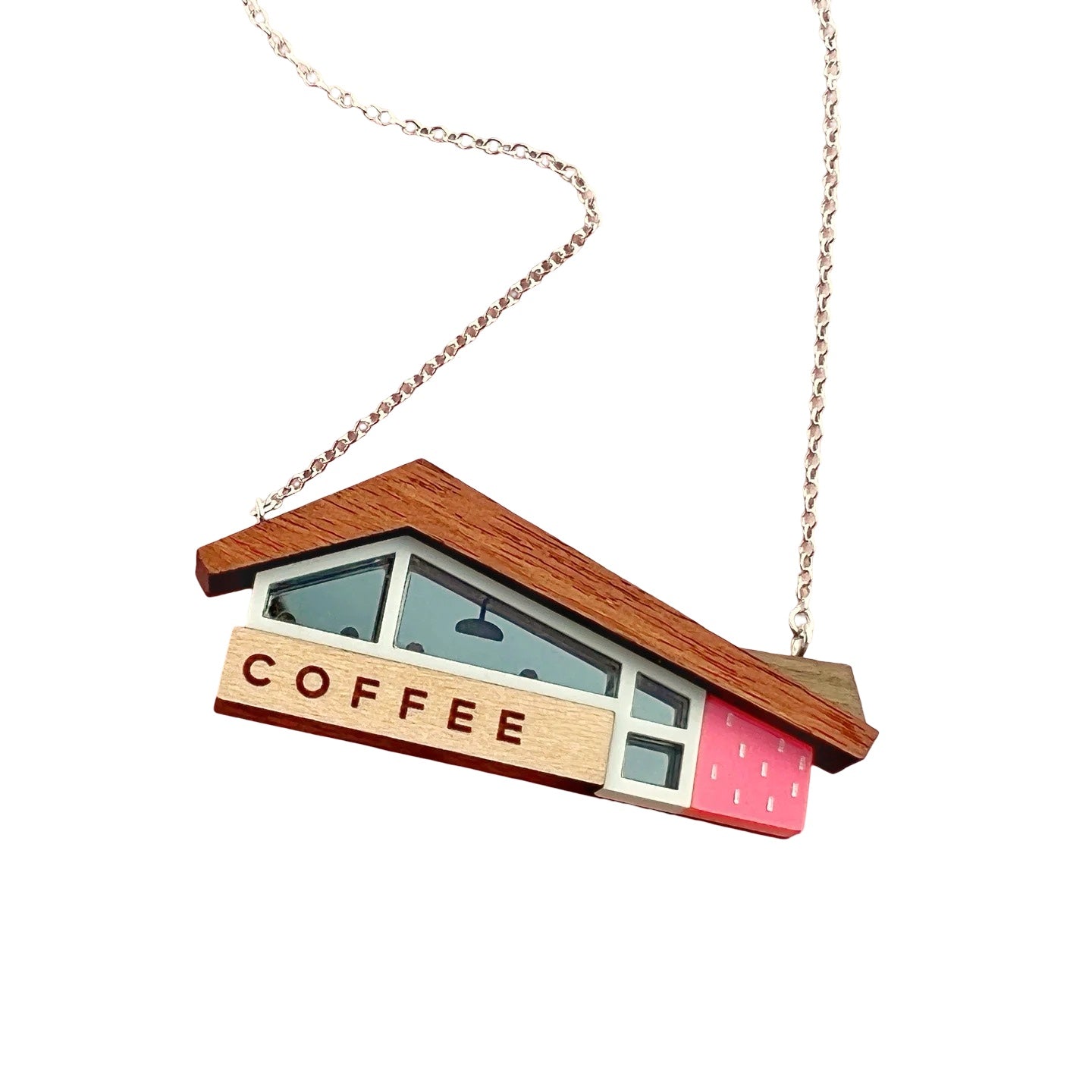 This necklace features a retro-inspired American coffee shop as a pendant, with a wooden roof and a coral pink wall.