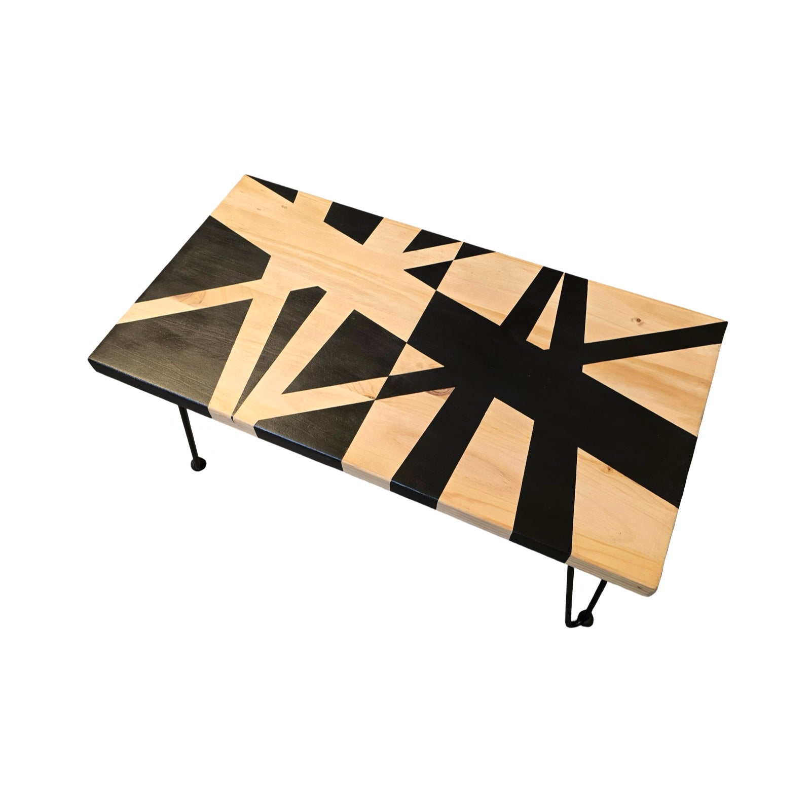 An upcycled coffee table with black hairpin legs and a bold black geometric design on a wooden surface, set against a white background.