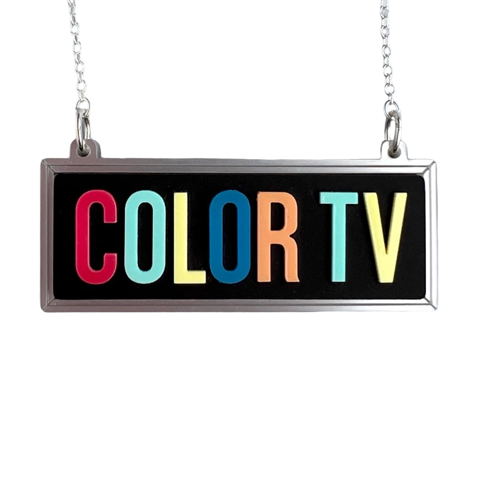 A necklace featuring a black rectangular acrylic pendant with the words COLOR TV in multicoloured lettering.
