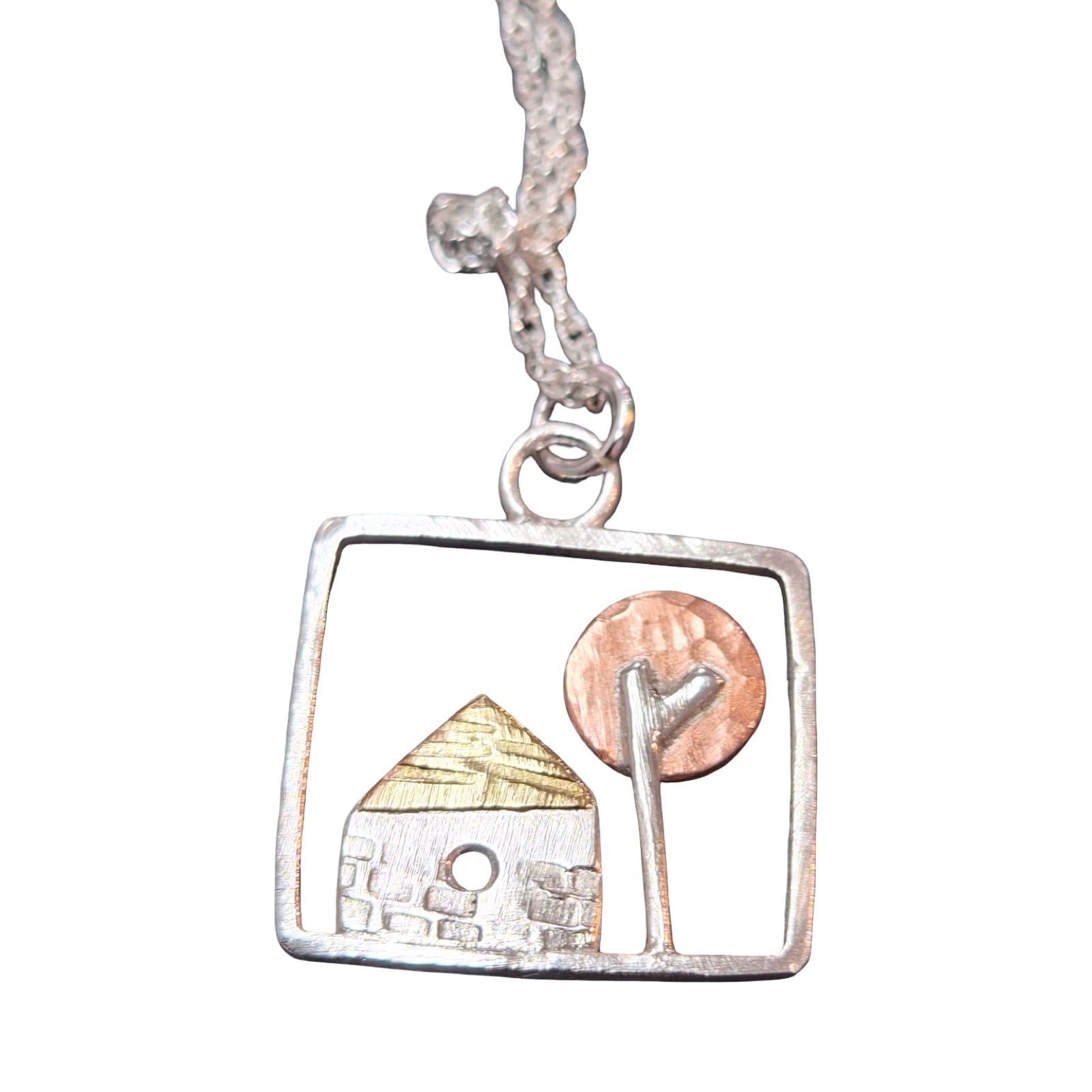Silver pendant with a square frame featuring a house and tree design on a white background.