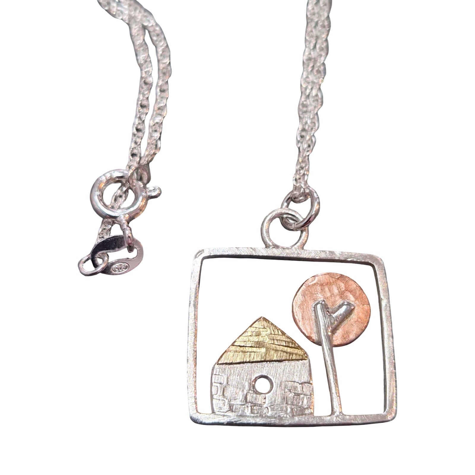 Necklace with a square pendant featuring a house and tree design on a white background.