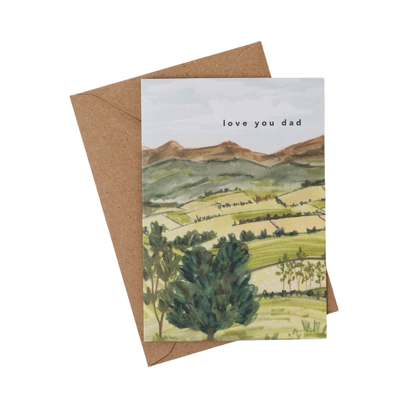 Greeting card with landscape illustration and 'love you dad' text, with a brown envelope.