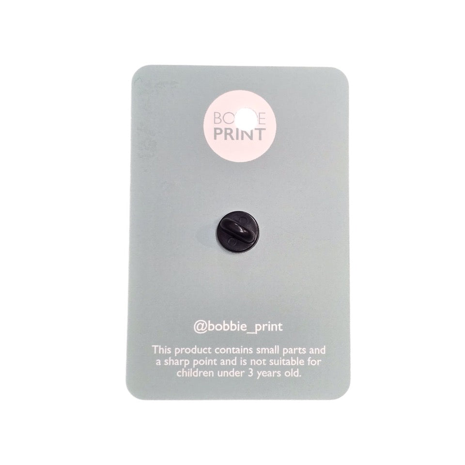 The back of the packaging for an enamel badge.