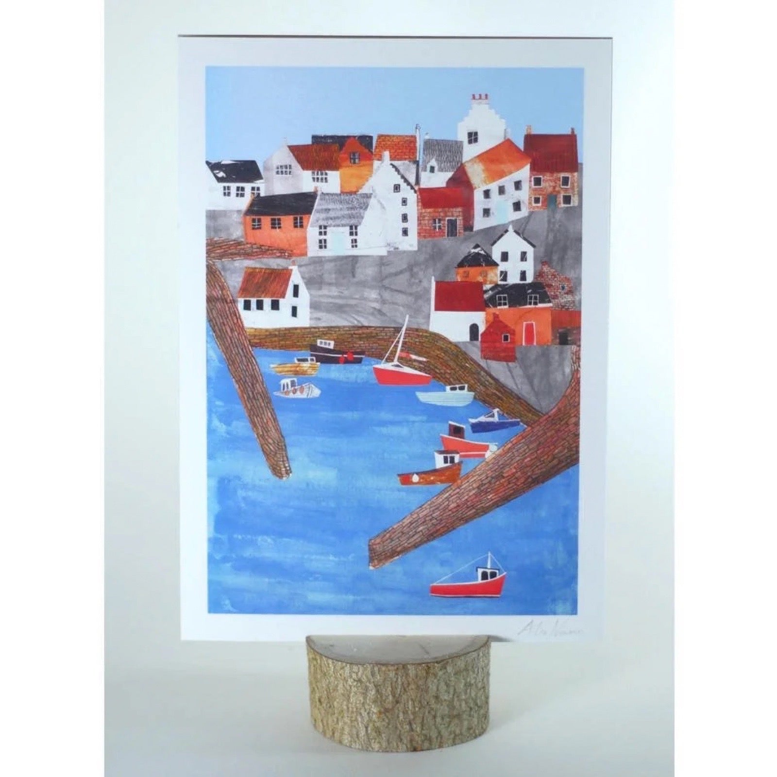 Framed artwork of a coastal scene with houses and boats.