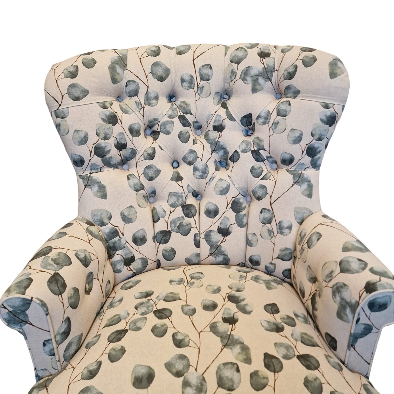 A hand-crafted cream linen armchair with green leaf pattern, button-back, cream binding, mahogany stained legs, and gold colored castors.