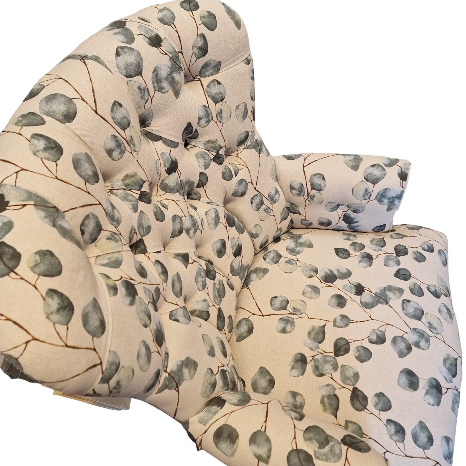 A hand-crafted cream linen armchair with green leaf pattern, button-back, cream binding, mahogany stained legs, and gold colored castors.