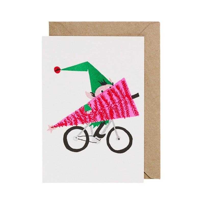 Christmas card featuring an elf cycling holding a large pink and red Christmas tree.