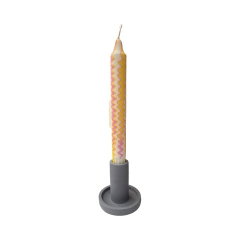 A cylindrical dinner candle holder with a lip around the bottom to catch any drips holding a blue dinner candle.