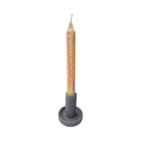 A cylindrical dinner candle holder with a lip around the bottom to catch any drips holding a blue dinner candle.