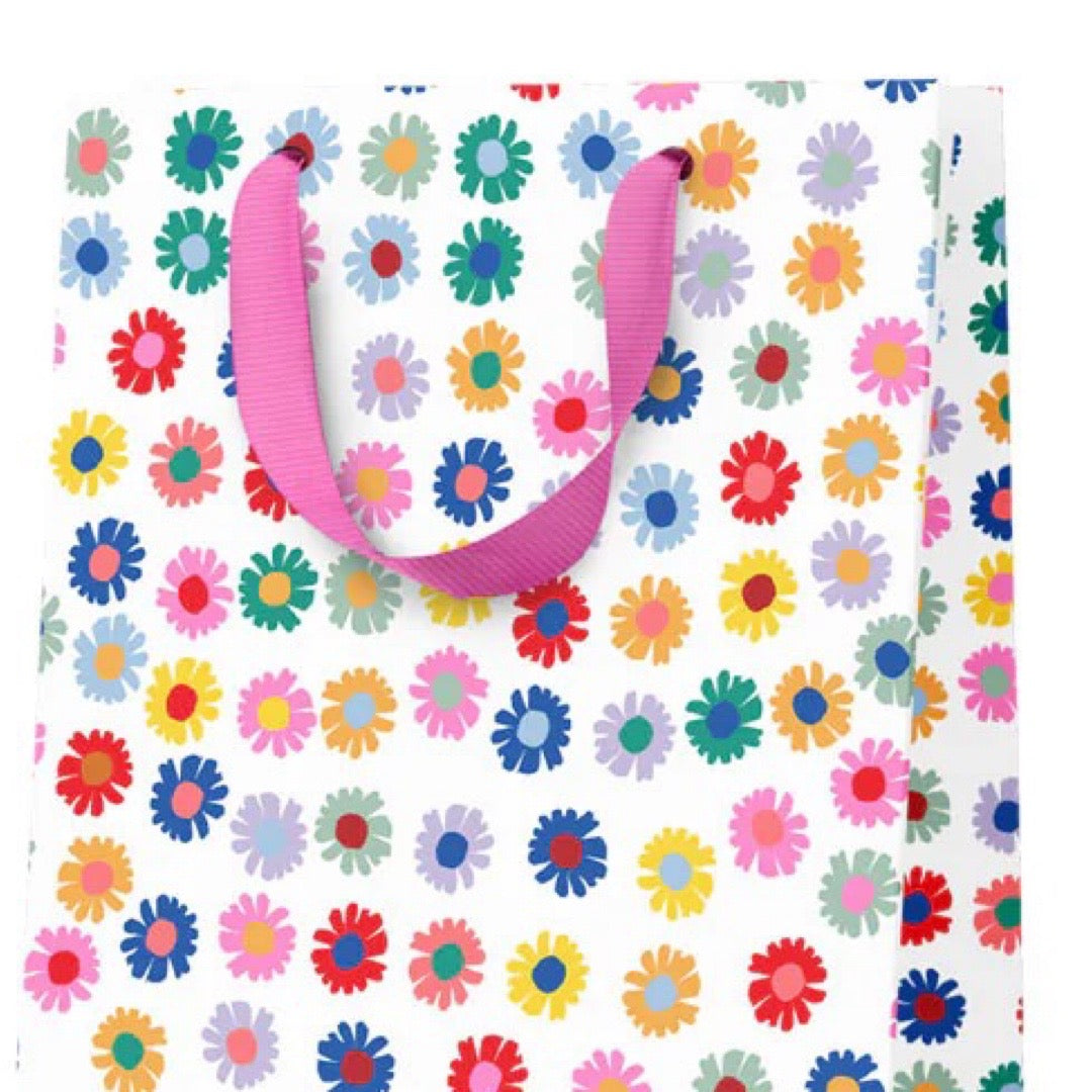 Floral-patterned gift bag with a pink handle on a white background.