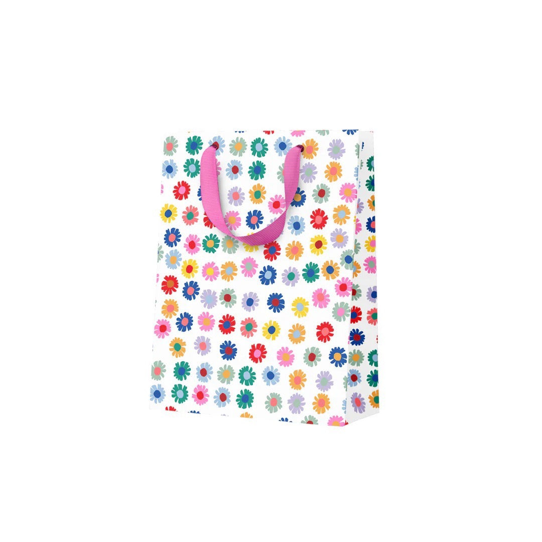 Colorful floral-patterned gift bag with pink handles on a white background.
