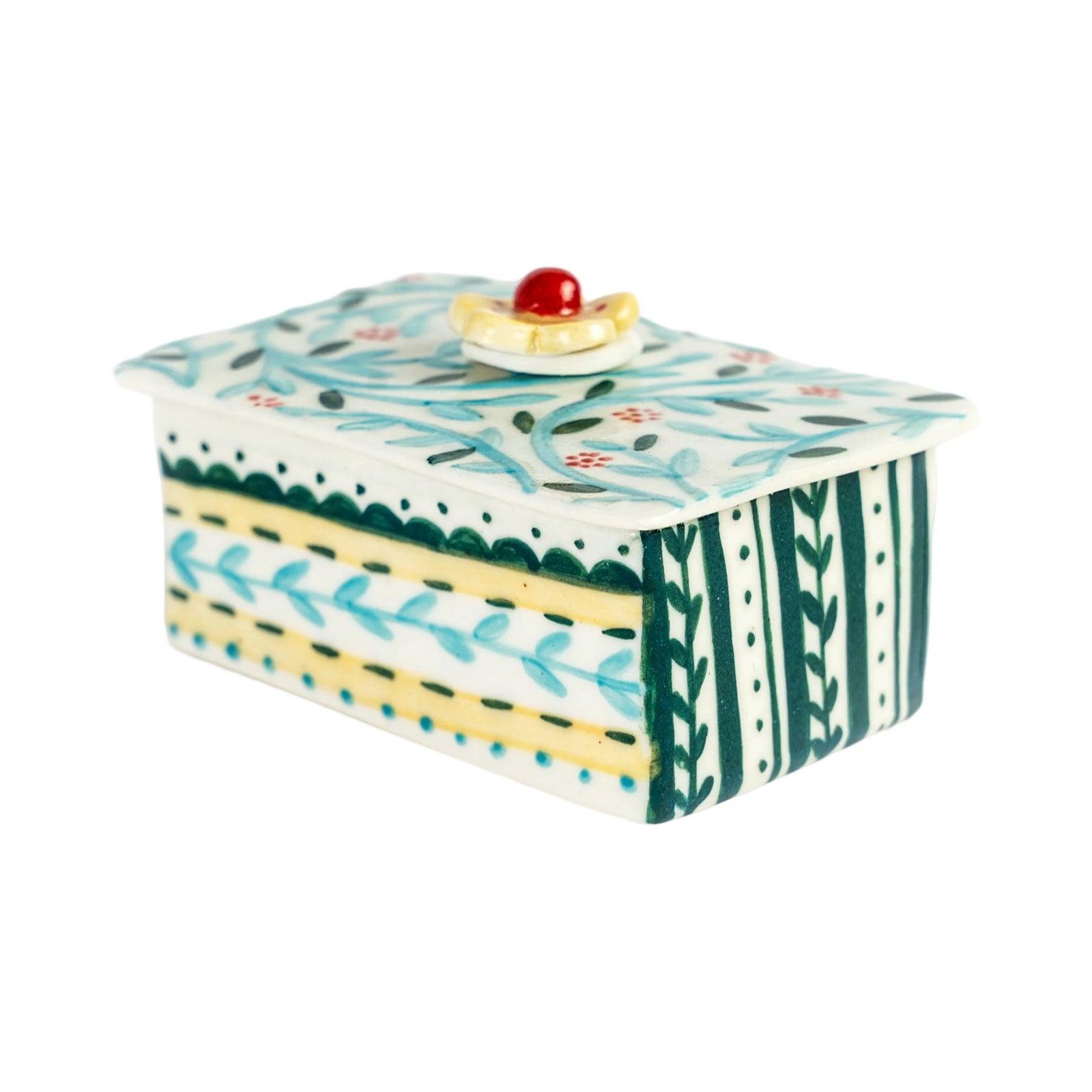 A ceramic trinket box with a multicoloured geometric pattern and a decorative cake on the lid.