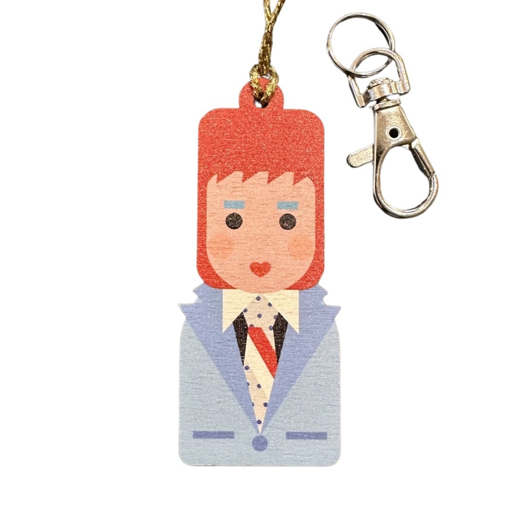 A wooden decoration in the shape of David Bowie wearing a suit, with a keyring attached.