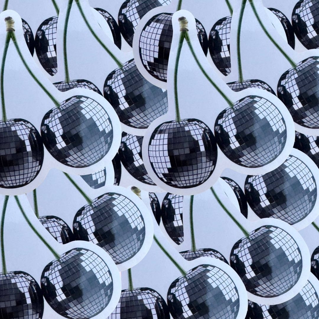 A pile of disco-ball cherry stickers with green stems on a pale blue background.