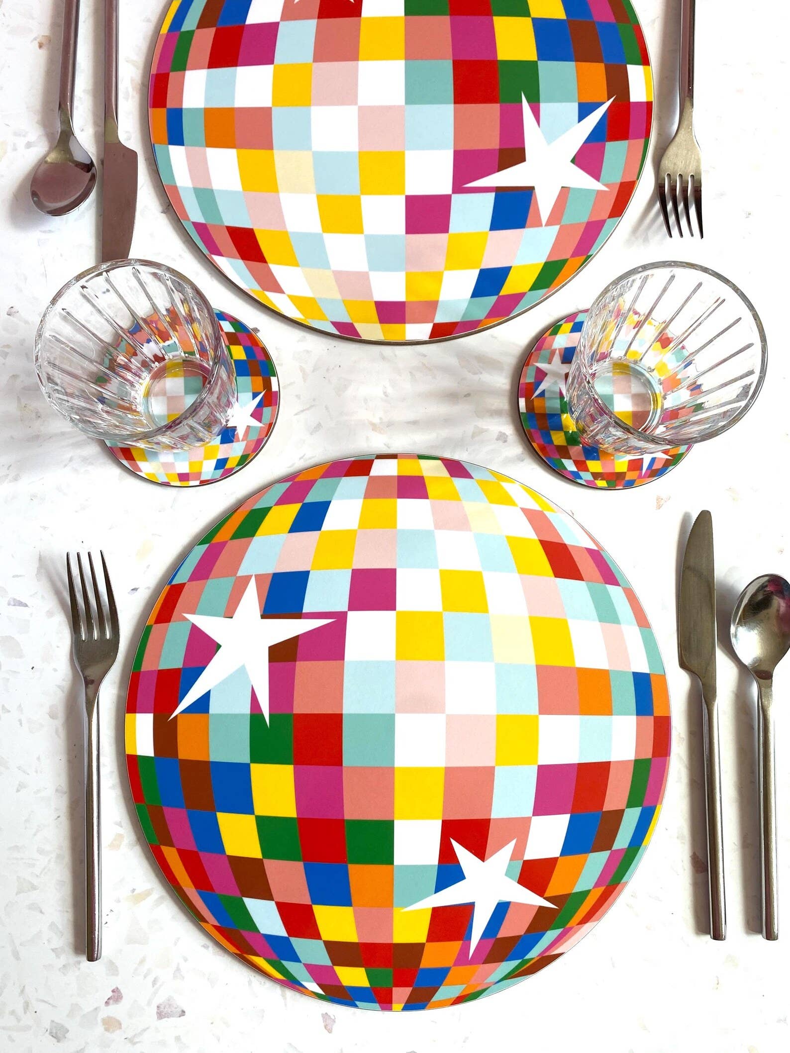 Colourful disco ball place mat on a table setting with cutlery and glasses.