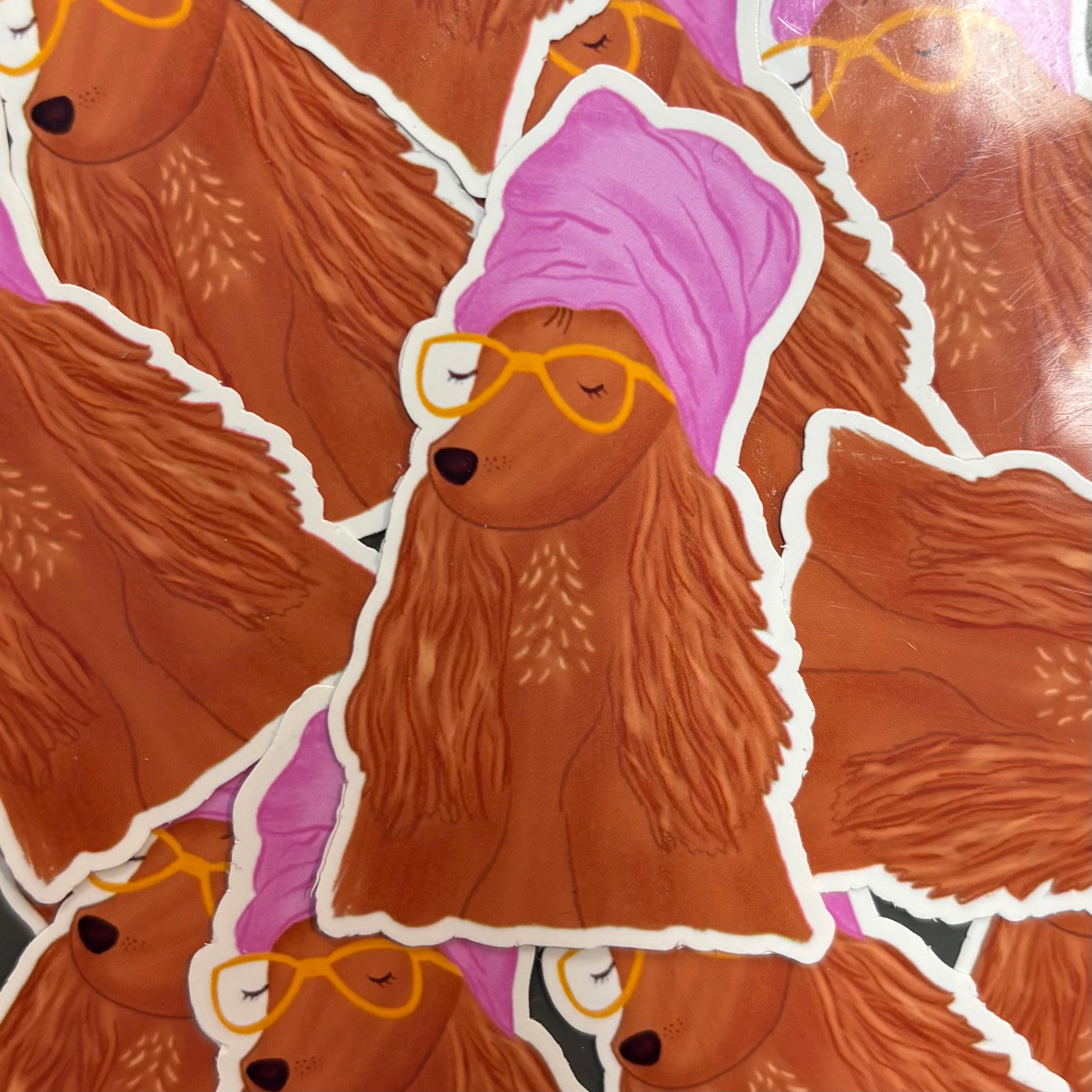 Pile of stickers of a dog wearing a pink bandana and yellow sunglasses.