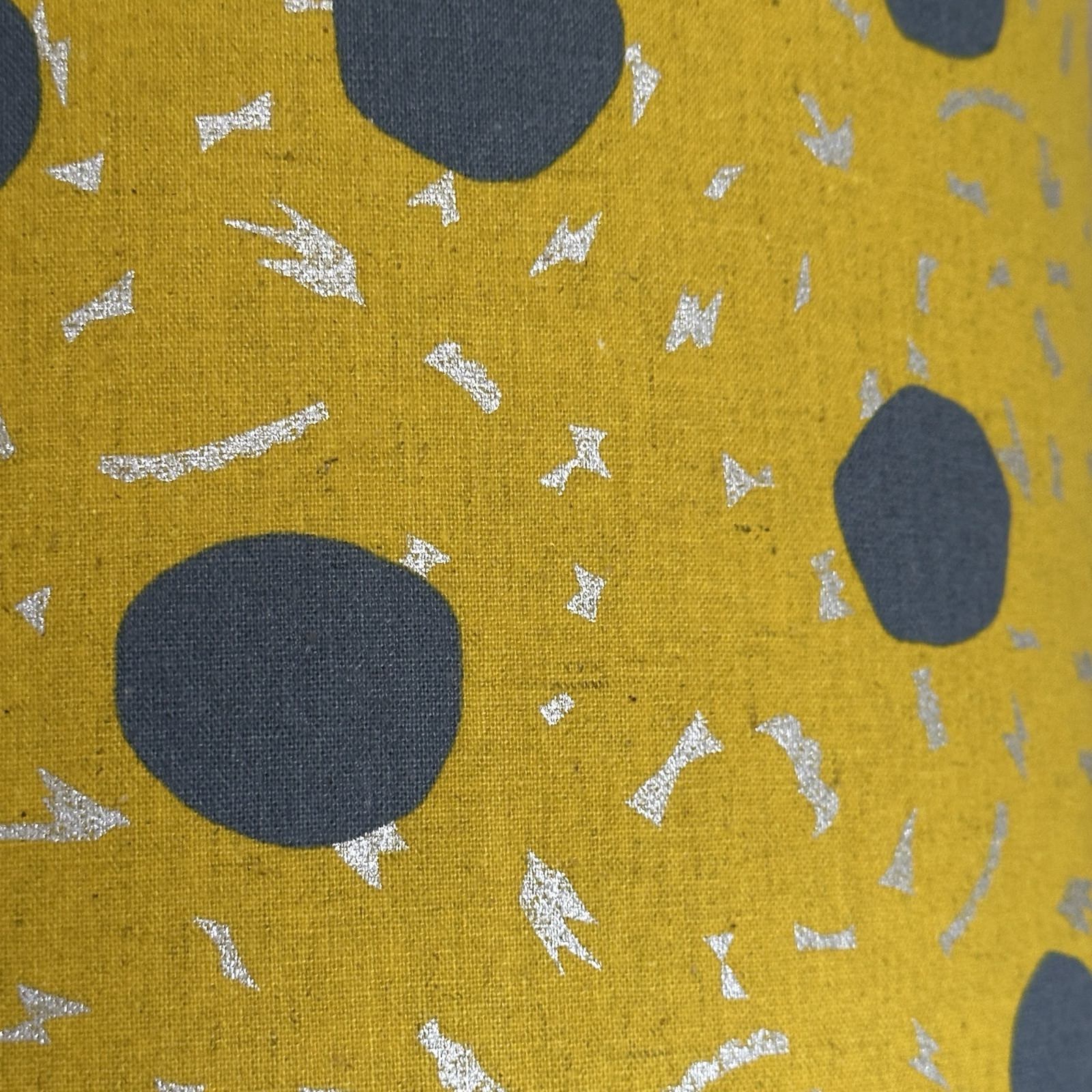 Mustard fabric with large grey spots and silver dashes