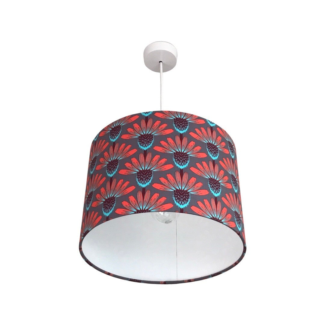 drum lampshade covered in grey fabric with red, brown and blue echinacea flowers.