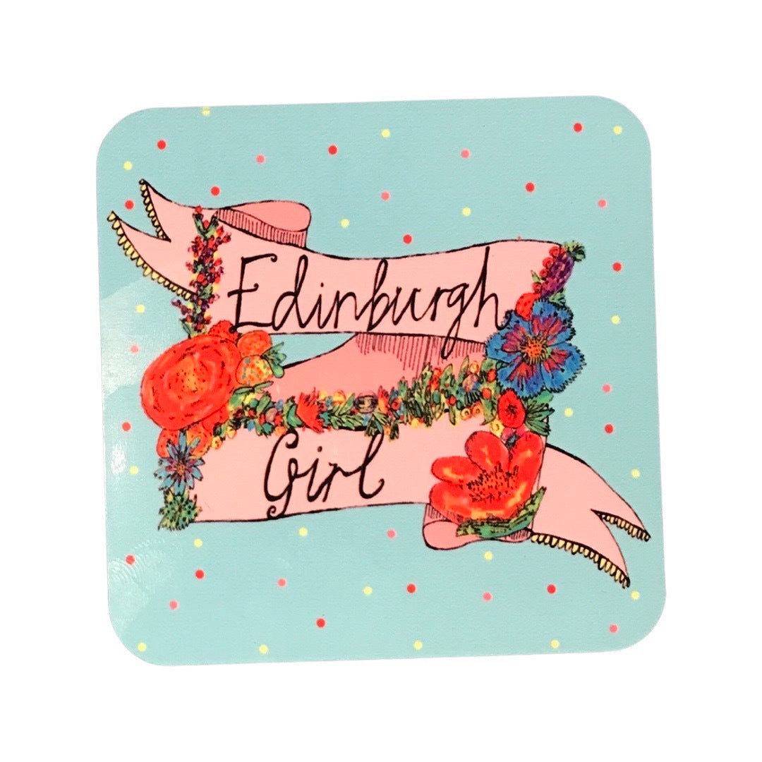 'Edinburgh Girl’ coaster featuring the text 'Edinburgh Girl' written inside a banner and surrounded by flowers on a blue background.