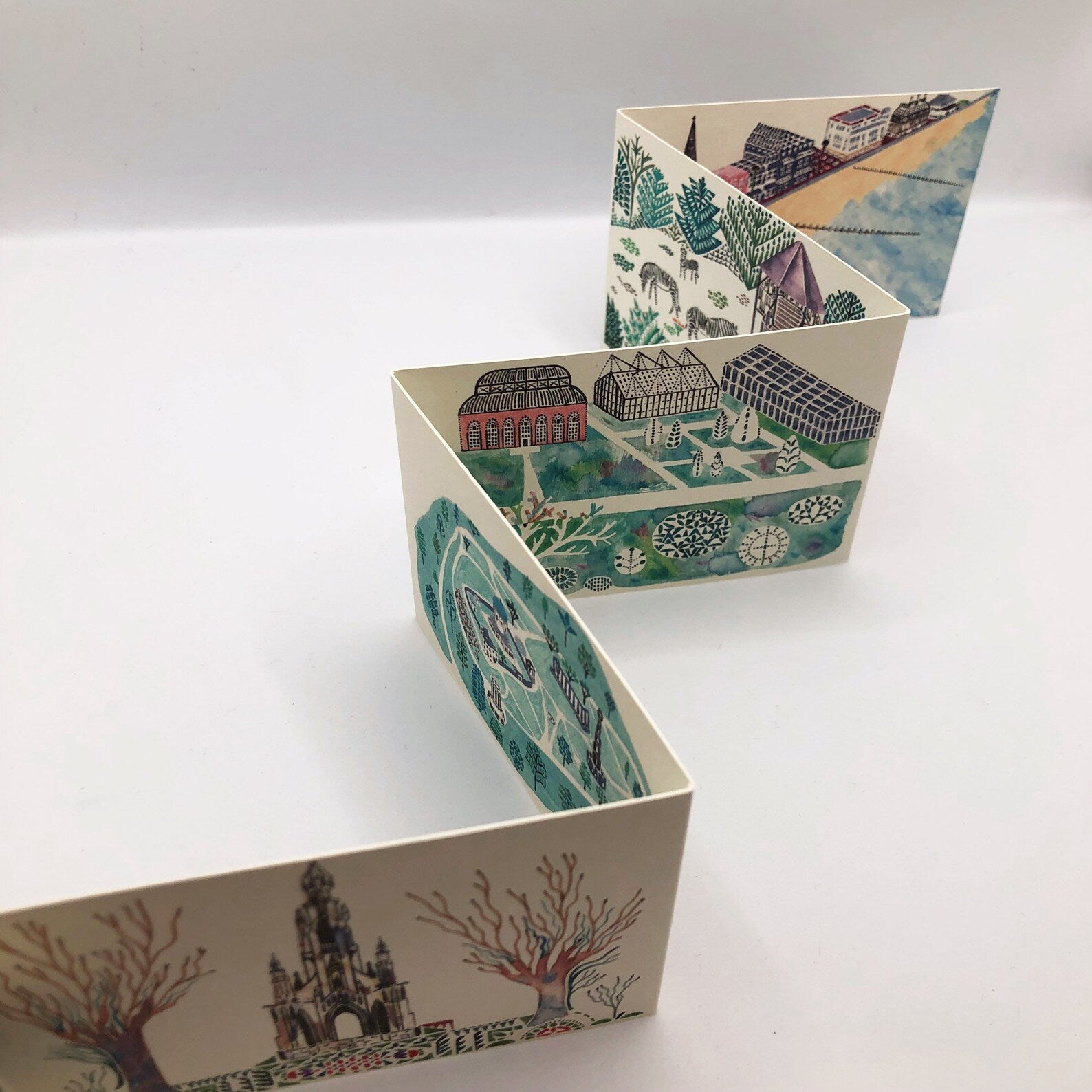 Folded paper with scenic illustrations on a white background.