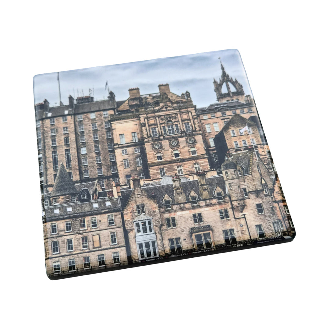 A square coaster with rounded corners featuring a printed photograph of historic Edinburgh buildings, shown at an angle on a plain white background.