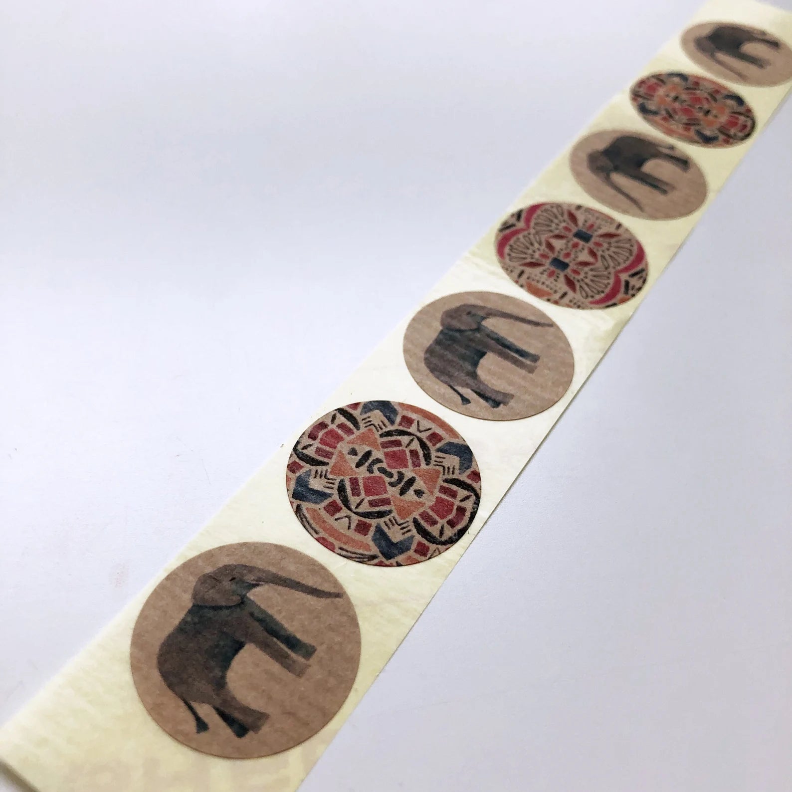 Roll of decorative stickers with elephant and circular patterns on a white background.