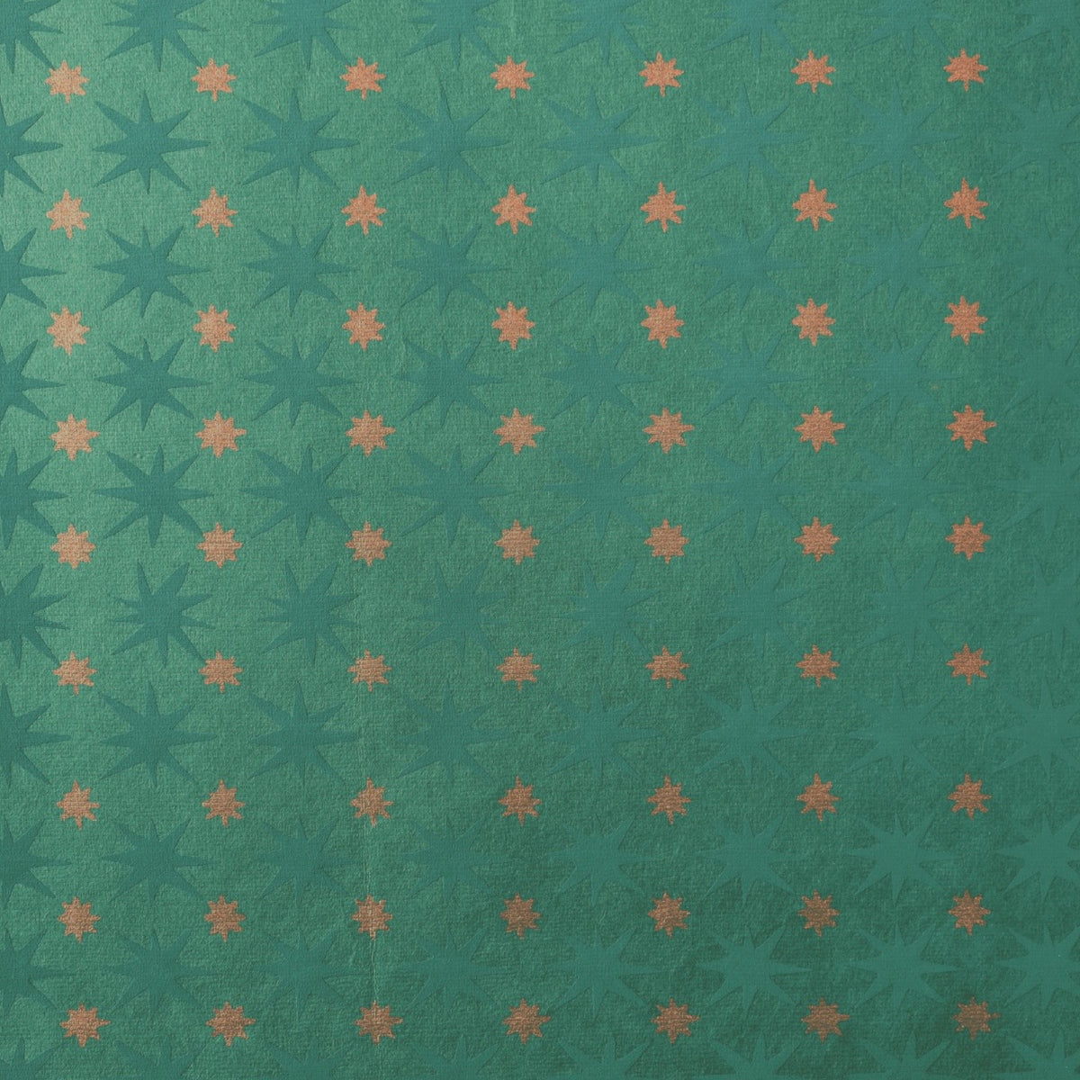 A close-up of wrapping paper featuring a repeating grid of starbursts in dark teal and muted orange on a teal-green background.